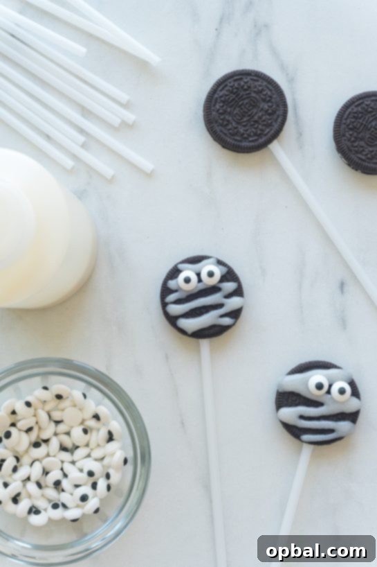 Halloween Mummy Oreo Pops 14 Several Mummy Oreo Pops with candy eyes drying on parchment paper, awaiting their final set