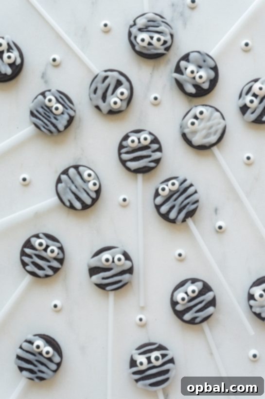 Halloween Mummy Oreo Pops 15 Finished Mummy Oreo Pops arranged on a decorative platter with autumn leaves, showcasing their cute and spooky design