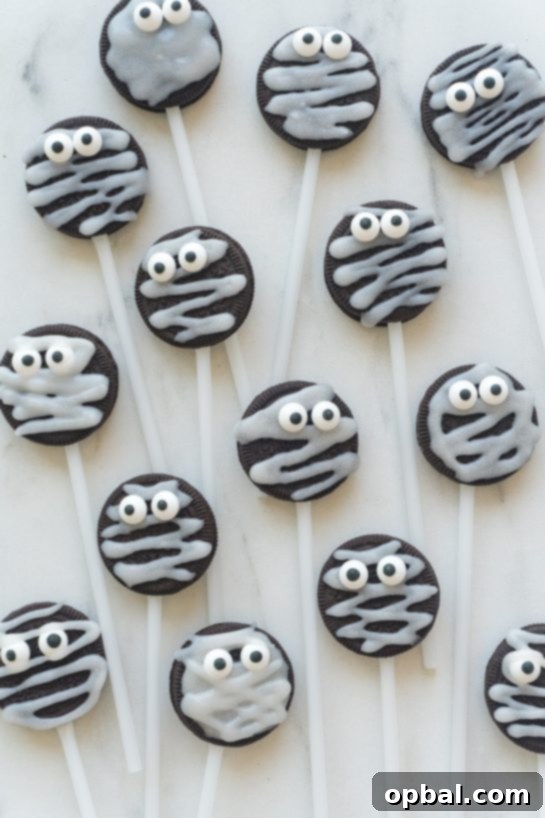 Halloween Mummy Oreo Pops 18 Overhead shot of more Halloween Mummy Oreo Pops on a dark surface, showcasing various designs and candy eye expressions