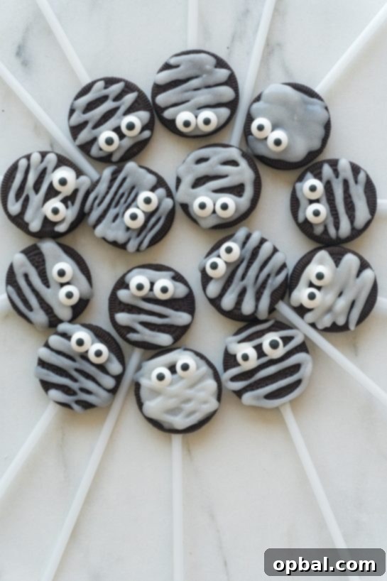 Halloween Mummy Oreo Pops 19 Group of finished Halloween Mummy Oreo Pops standing upright in a festive Halloween container, ready to be served