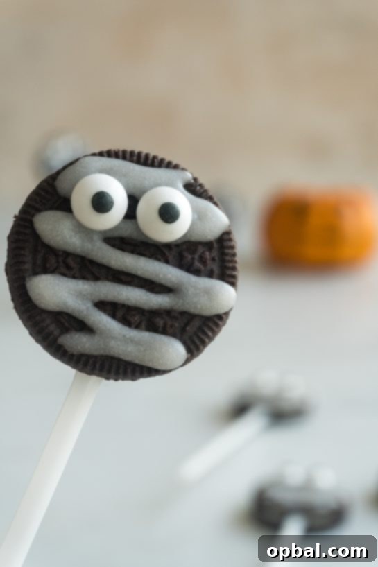 Halloween Mummy Oreo Pops 9 Close-up of a finished Mummy Oreo Pop with white icing and two candy eyes, ready for Halloween