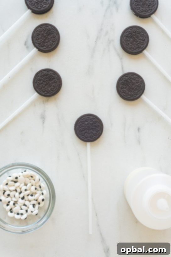 Halloween Mummy Oreo Pops 10 Two Oreo cookies with lollipop sticks inserted, sitting on parchment paper, awaiting their mummy transformation