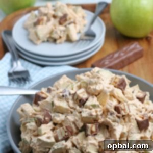 Caramel Apple Snickers Delight 7 A beautifully presented Caramel Apple Snickers Salad, vibrant with green apples, creamy whipped topping, and generous pieces of Snickers candy bars. This dish is perfect for any festive table.