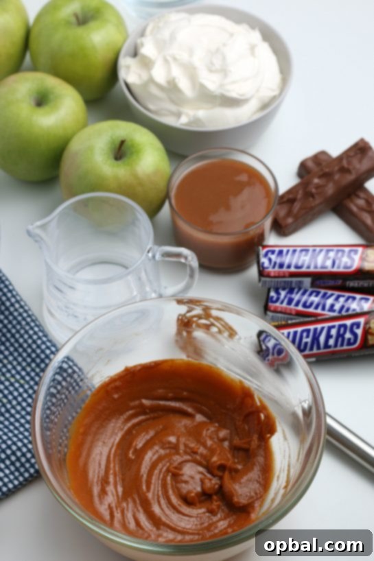 Caramel Apple Snickers Delight 4 A close-up shot of a bowl where smooth caramel sauce is being mixed, forming the sweet base for the Caramel Apple Snickers Salad.