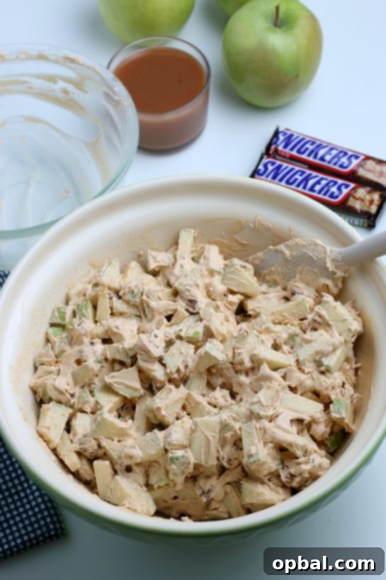 Caramel Apple Snickers Delight 8 A vibrant mix of green apples, chopped Snickers, and creamy whipped topping, perfectly combined in a bowl. This Caramel Apple Snickers Salad is ready for chilling.