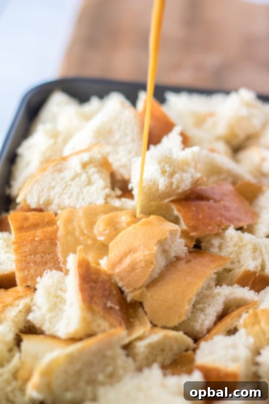 Spiced Sweet Potato French Toast Bake 6 A rich, creamy sweet potato and egg mixture being poured over a bed of cubed bread in a baking dish, ensuring every piece is coated for the French Toast Casserole.