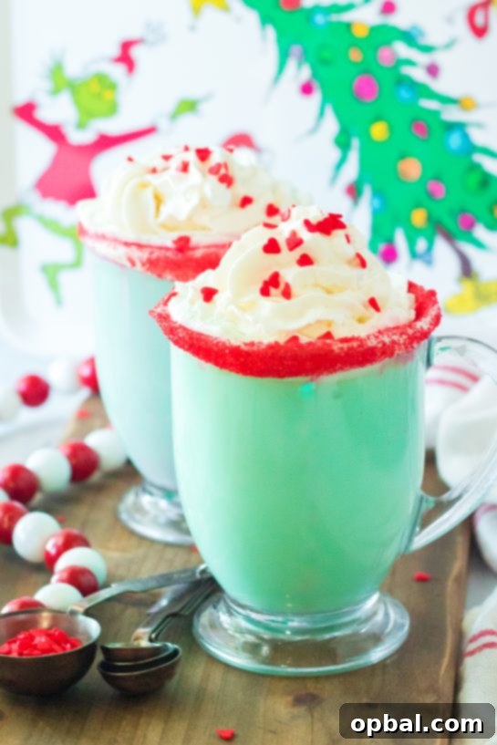 Grinchy Christmas Delight 12 Full shot of a festive green Grinch Hot Chocolate with whipped cream, red sprinkles, and a heart-shaped candy.