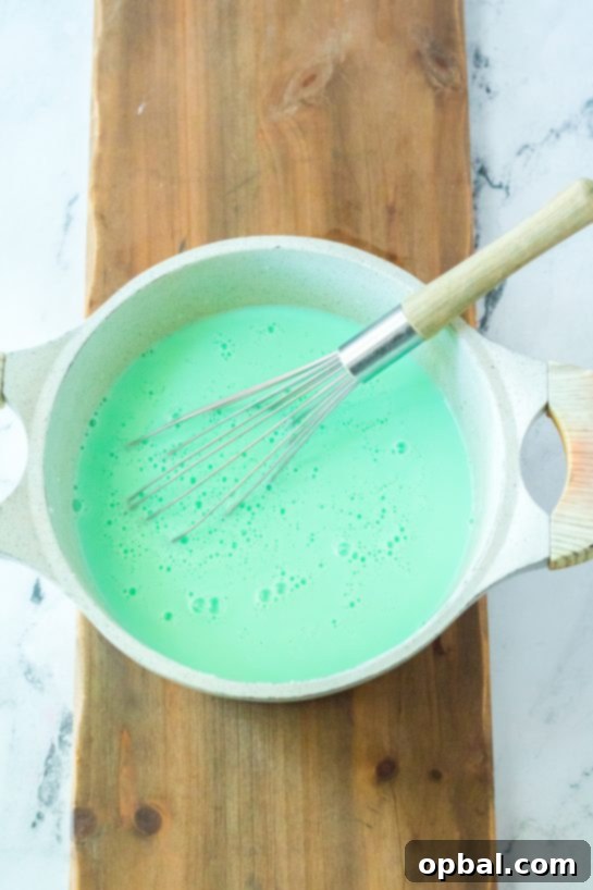 Grinchy Christmas Delight 6 White chocolate chips melting in milk in a saucepan, a key step for making creamy Grinch Hot Chocolate.