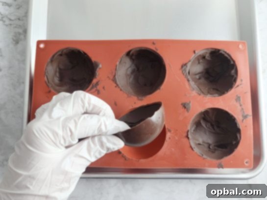 Carefully removing hardened chocolate half-spheres from molds.