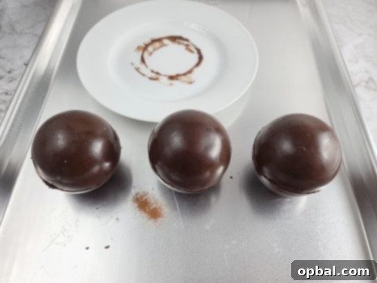 Sealing two chocolate half-spheres together to form a complete hot chocolate bomb.