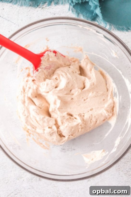 Frosted Cinnamon Roll Dip 7 Cream cheese being mixed to make this easy Cinnamon Roll Dip recipe