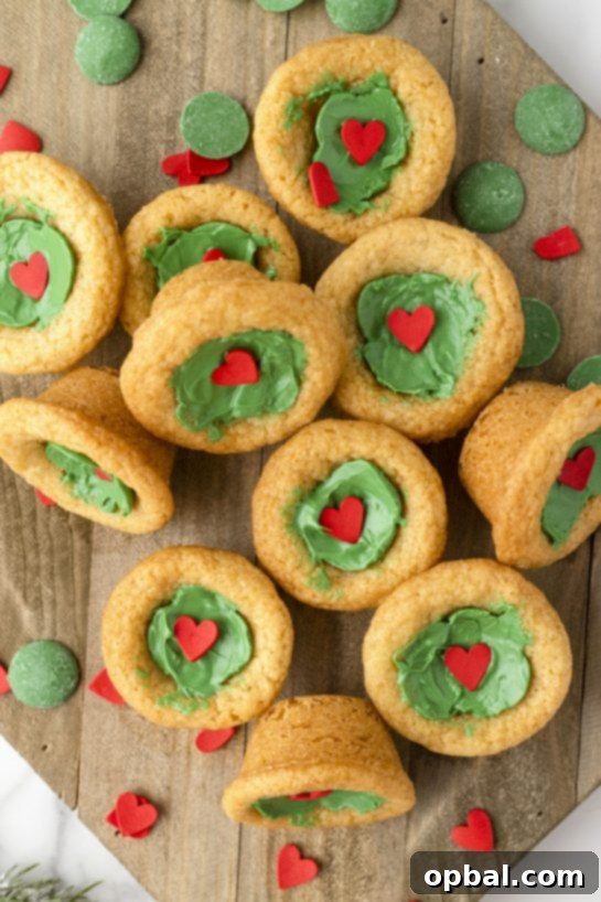 Grinchy Holiday Cookie Cups 2 Grinch Cookie Cup Bites recipe is inspired by Dr. Seuss’s How the Grinch Stole Christmas! They are chewy sugar cookies that have been colored green and adorned with a festive red heart for a fun holiday dessert!