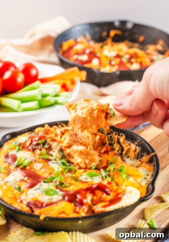 Ultimate Game Day Buffalo Chicken Dip 6 A serving of delicious Buffalo Chicken Wing Dip with a scoop missing, inviting guests to dig in.