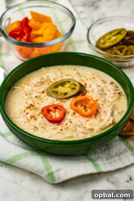 Slow Cooker Zesty Green Chili Chicken Enchilada Soup 2 Rich and creamy Crock Pot Green Chili Chicken Enchilada Soup, garnished with fresh cilantro and a dollop of sour cream, served in a rustic bowl.