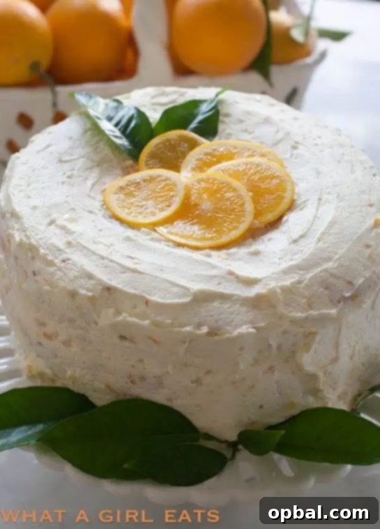 A generous slice of Orange Cream Angel Food Cake, showcasing its airy texture and creamy orange glaze, on a white plate.