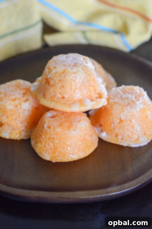 Orange Creamsicle Cake Bites, coated in a sweet glaze, arranged artfully on a serving dish, ready to be picked up.