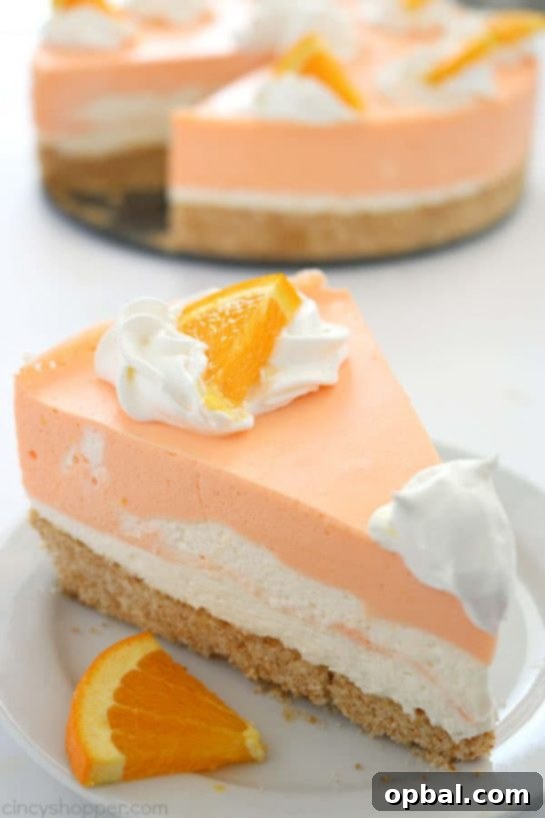 A slice of No-Bake Orange Creamsicle Cheesecake with a Nilla wafer crust and creamy orange layers, garnished with fresh orange zest.