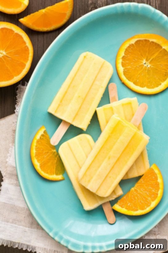 Vibrant Orange Creamsicle Yogurt Pops standing upright, showcasing their layered orange and white appearance, ready to be enjoyed.