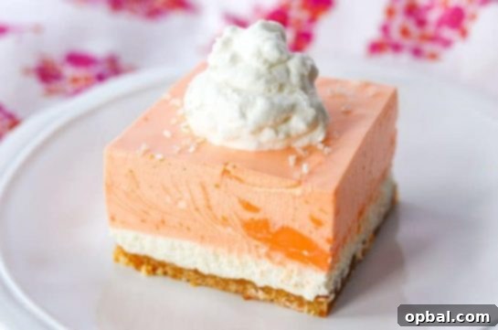 Orange Creamsicle Dream Bars cut into squares, showing the distinct layers of cookie crust, vanilla cheesecake, and orange cream topping.