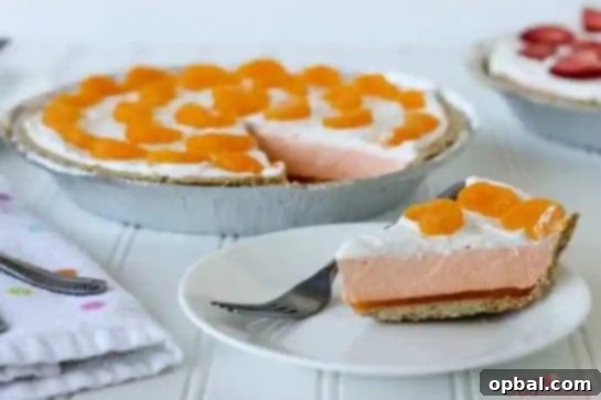 A beautifully presented slice of Orange Creamsicle Pie, showcasing its creamy orange filling and golden crust, with a fork ready to taste.
