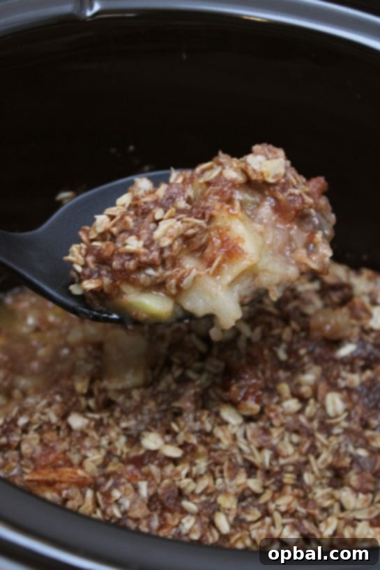 Slow Cooker Apple Crisp cooling in the Crock Pot, showing the golden oat crumble topping