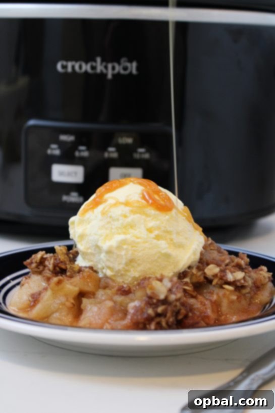 Warm Crock Pot Apple Crisp topped with a rich caramel sauce drizzle