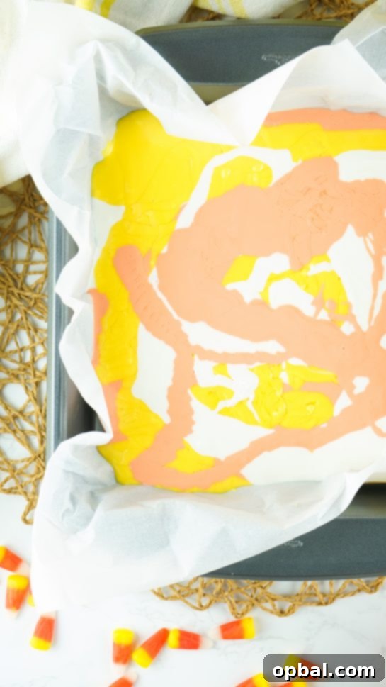 Tri-Color Candy Corn Fudge 5 Swirling melted white chocolate in a bowl for the No-Bake Candy Corn Fudge recipe, creating a smooth base.