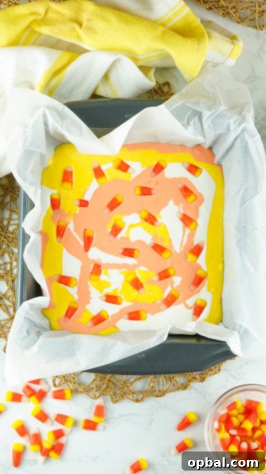 Tri-Color Candy Corn Fudge 6 Placing candy corn on top of the swirled melted white chocolate for the No-Bake Candy Corn Fudge recipe, adding a festive garnish.