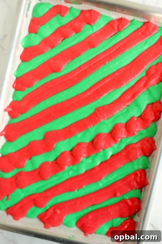 Festive Yule Log Cake 5 Piping contrasting colored cake batter into a jelly roll pan in a diagonal pattern, preparing for a beautiful swirl design in the Christmas Cake Roll.