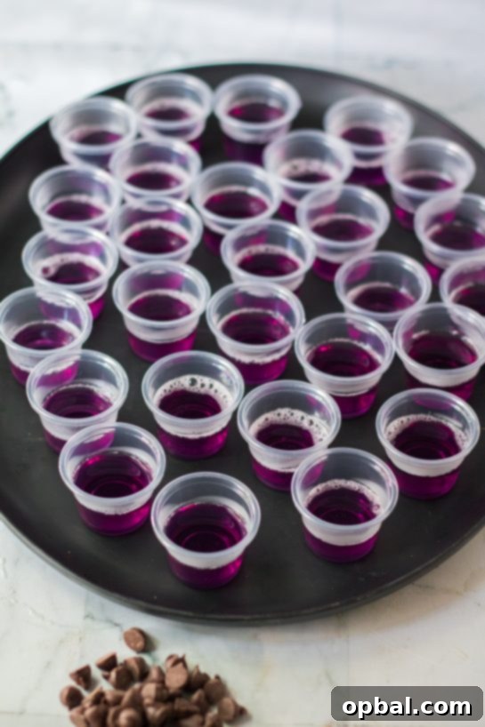 Halloween Spirit Shots 6 Creating a multi-layered effect by pouring the purple Jello Shot mixture into individual plastic cups.
