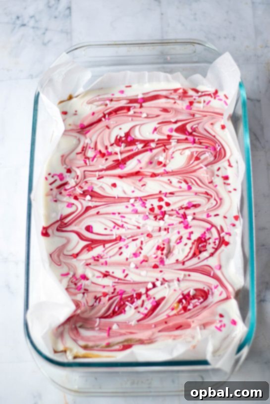 Sweet Valentine's Millionaire Bars 8 A knife gently swirling vibrant red and pink melted chocolate into a layer of white chocolate, creating an an elegant marbled effect on the Valentine's Day Millionaire Bars.