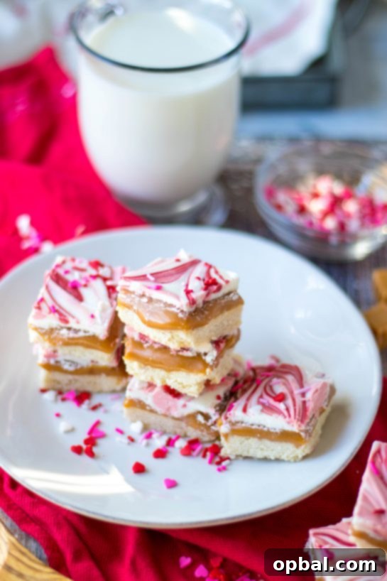 Sweet Valentine's Millionaire Bars 9 The finished Valentine's Day Millionaire Bars, perfectly sliced and showcasing their distinct layers of shortbread, caramel, and swirled white and colored chocolate with festive sprinkles.