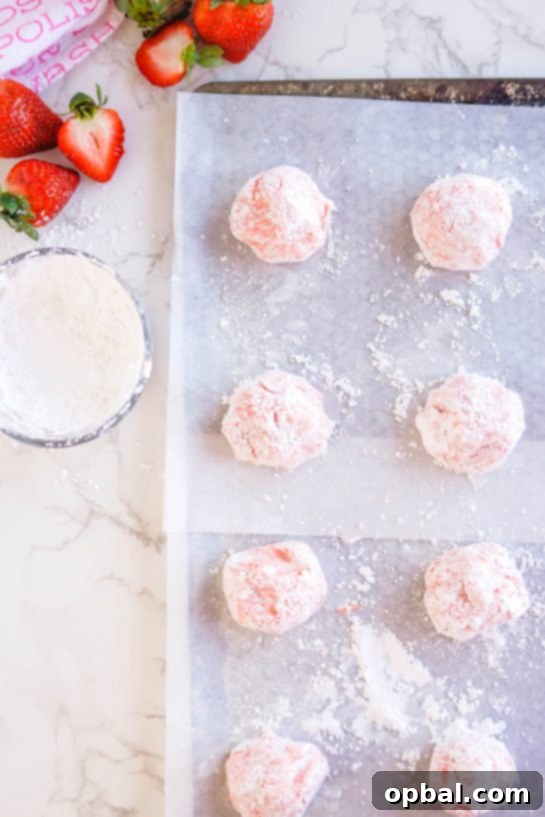 Luscious Strawberry Crinkles 5 Strawberry Crinkle Cookie dough balls, generously coated in powdered sugar, ready to go into the oven for baking.