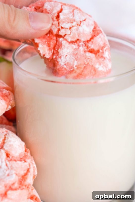 Luscious Strawberry Crinkles 10 Image of a Strawberry Crinkle Cookie being dunked in milk, ideal for a Valentine's Day party or a sweet treat.
