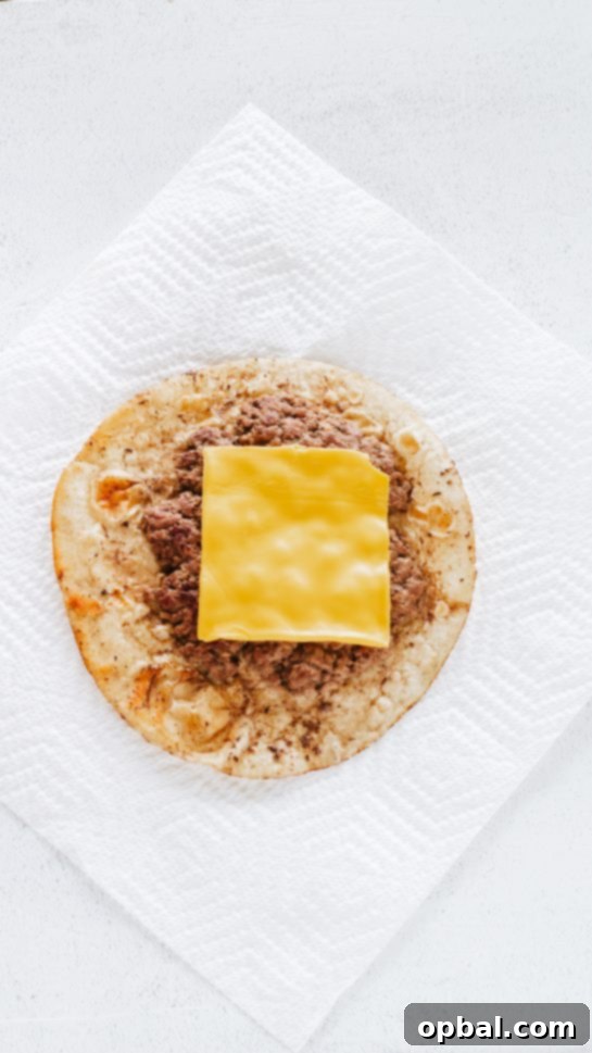 Viral Big Mac Tacos 5 Adding a slice of American cheese to the cooked ground beef on the tortilla, a crucial step for melting perfection in Big Mac Tacos.