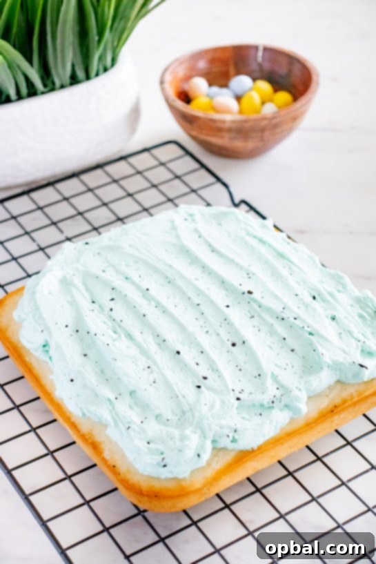 Robin's Egg Easter Cakelets 7 A smooth, light blue frosting being expertly spread across the top of the cooled Easter Speckled Egg Snack Cake with an offset spatula.