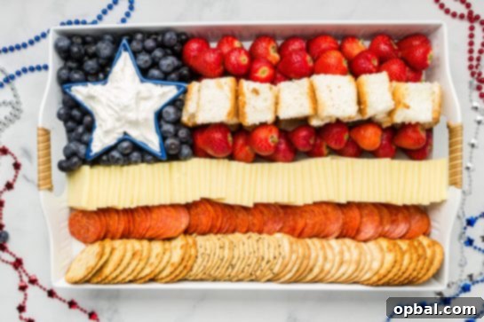 22 Firecracker Flavors for the Fourth 20 Budget-friendly Flag Charcuterie Board recipe for the 4th of July, featuring a mix of crackers, meat, cake, and berries to feed a crowd.