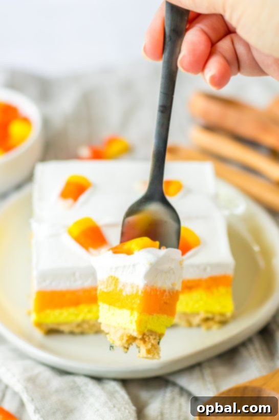 Decadent Candy Corn Delight 8 Close-up of a slice of the Candy Corn Lush recipe that is always a favorite at parties and is a make-ahead fall Halloween dessert that’ll make all ghouls go wild!