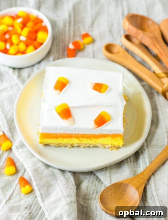 Decadent Candy Corn Delight 9 Overhead photo of a slice of the Candy Corn Lush recipe that is always a favorite at parties and is a make-ahead fall Halloween dessert that’ll make all ghouls go wild!