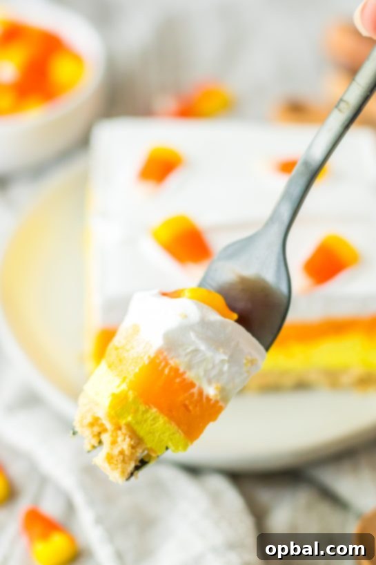 Decadent Candy Corn Delight 10 Close-up of a slice of the Candy Corn Lush recipe that is always a favorite at parties and is a make-ahead fall Halloween dessert.