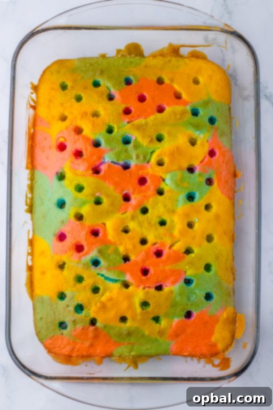 Springtime Easter Poke Cake 6 Poking holes in the colored batter for the Easter poke cake recipe after it comes out of the oven.