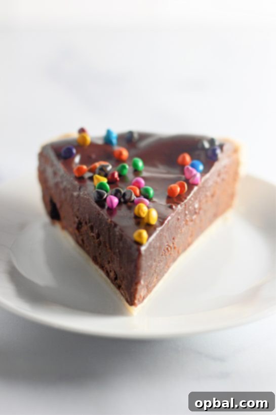 Starlight Sprinkled Brownie Pie 10 A perfectly plated slice of Cosmic Brownie Pie, ready to be enjoyed, showcasing the beautiful layers of crust, brownie, and ganache with colorful sprinkles.