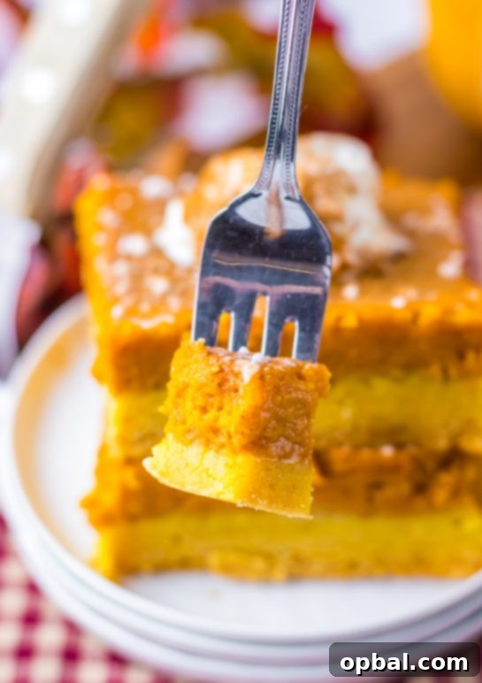 A perfectly baked slice of Pumpkin Gooey Butter Cake, showcasing its decadent, soft texture and rich pumpkin flavor, served on a fork for a tempting close-up.