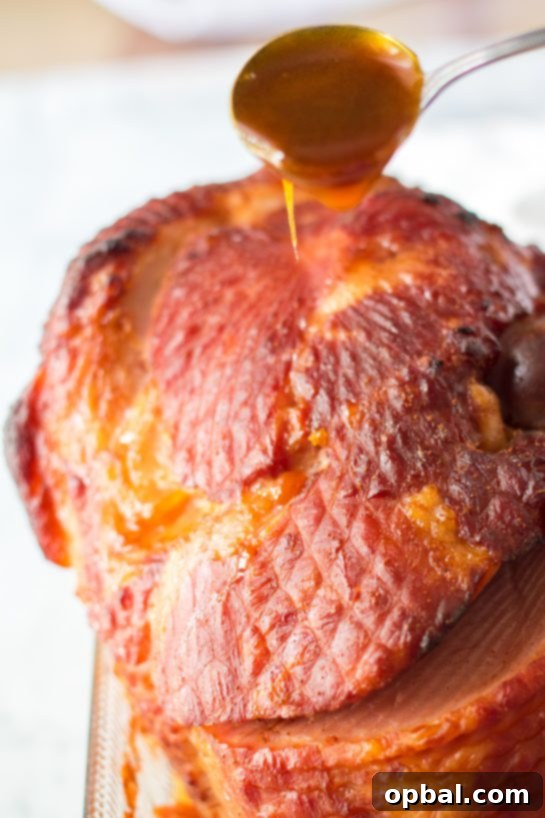 Christmas Glazed Ham 5 Pouring the thick, aromatic orange, honey, and brown sugar glaze over the spiral-sliced Christmas ham, creating a perfect coating.