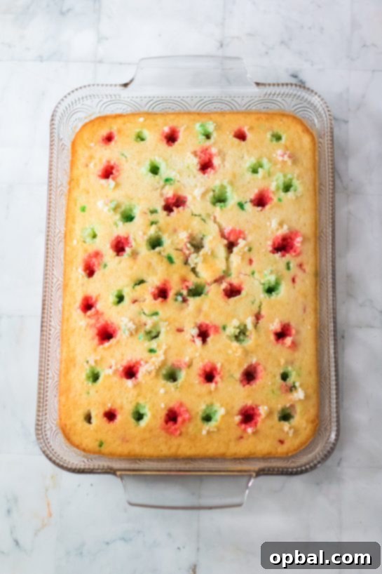 Holiday Spirit Poke Cake 6 Photo of pouring the Jell-o mixture onto the Christmas Poke Cake