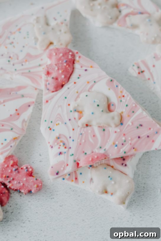 Festive No-Bake Animal Cracker Bark 2 No-Bake Circus Cookie Bark dessert recipe featuring colorful circus animal cookies on a creamy white chocolate base, sprinkled with rainbow sprinkles.
