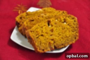 A close-up shot of a thick slice of white chocolate pumpkin bread, showing the moist crumb and melted white chocolate chips.