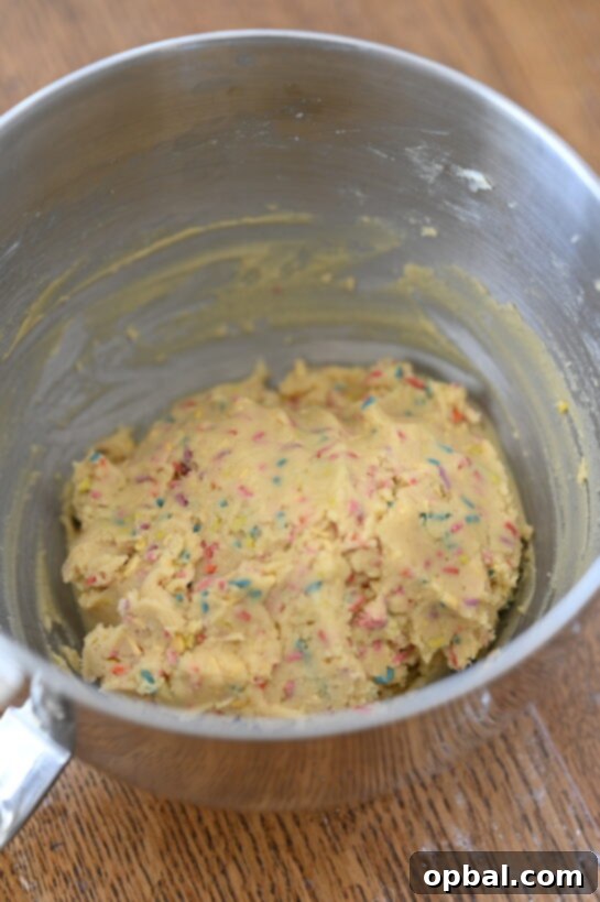 Mixing ingredients for Soft Sprinkle Sugar Cookies. Butter, sugar, and other ingredients being combined in a bowl.
